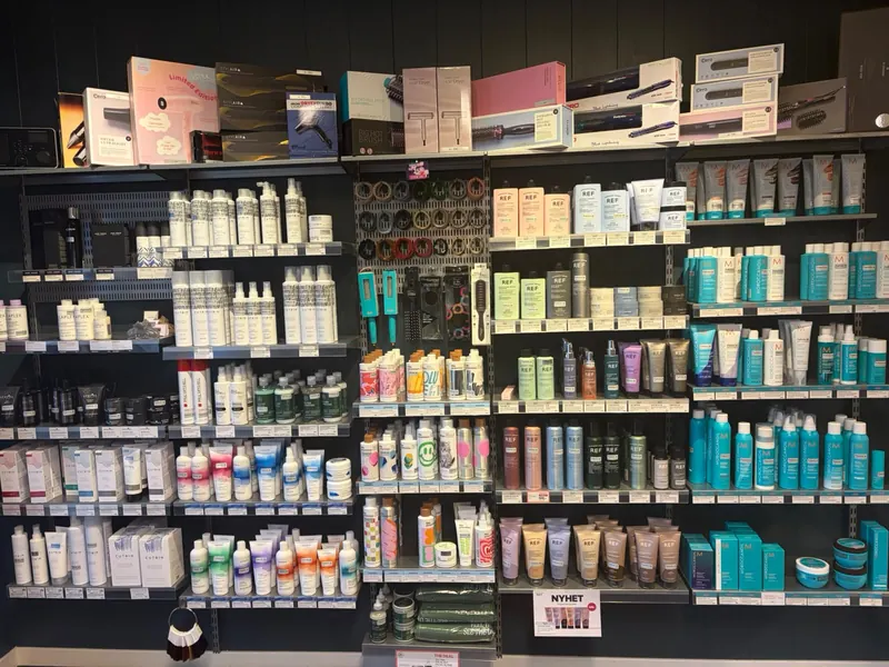 Produkthylla i salongen på Myre, med hårpleie, stylingprodukter, børster og stylingverktøy.