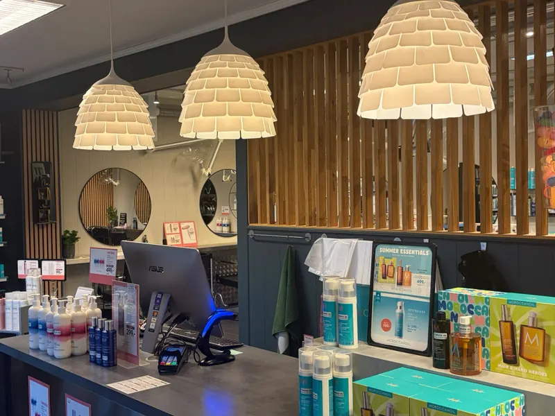 Resepsjonen hos Føhnix, med lyse pendellamper, tredetaljer og hårprodukter på disken.